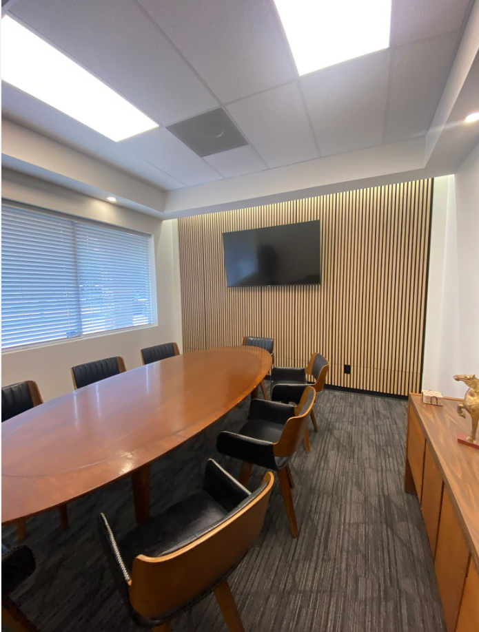 conference room with oval table, leather chairs, and wood-slat feature wall