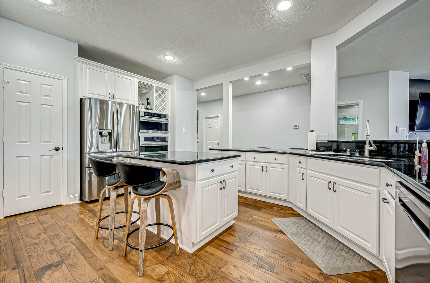 white kitchen with black countertops, island seating, and stainless appliances