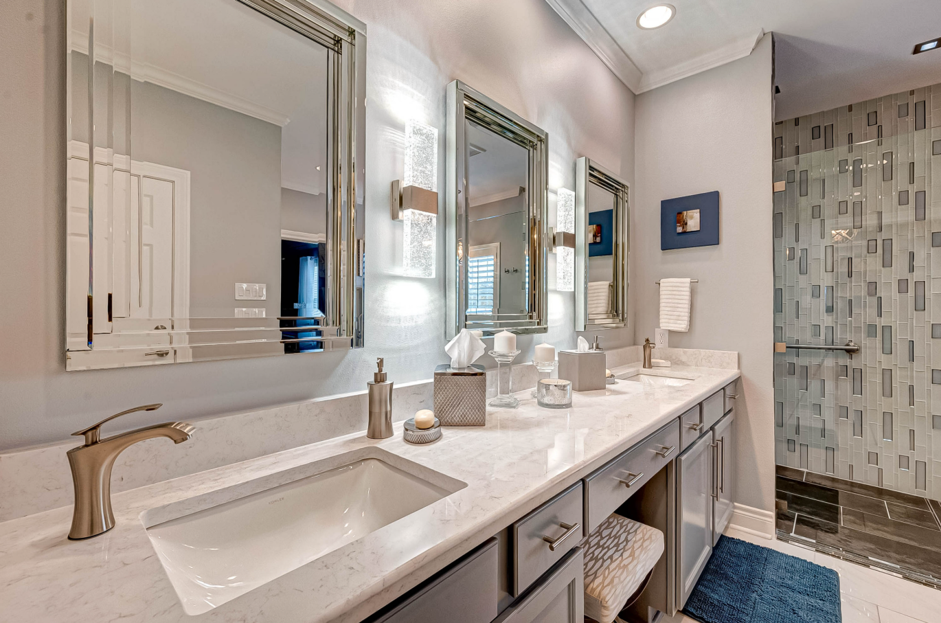 close view of upgraded double vanity with illuminated mirrors and quartz countertops