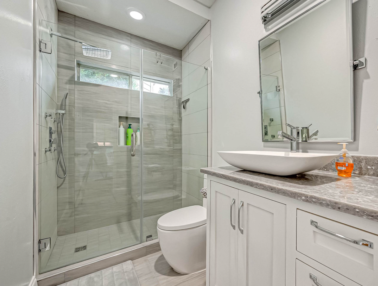 secondary bathroom with frameless glass shower, rain head, and vessel sink vanity