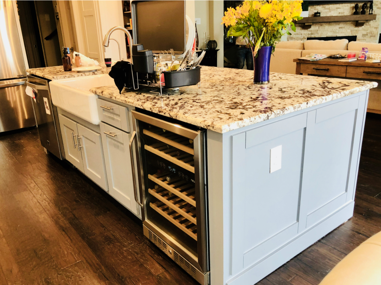 large kitchen island with farm sink, wine refrigerator, and custom panel detailing