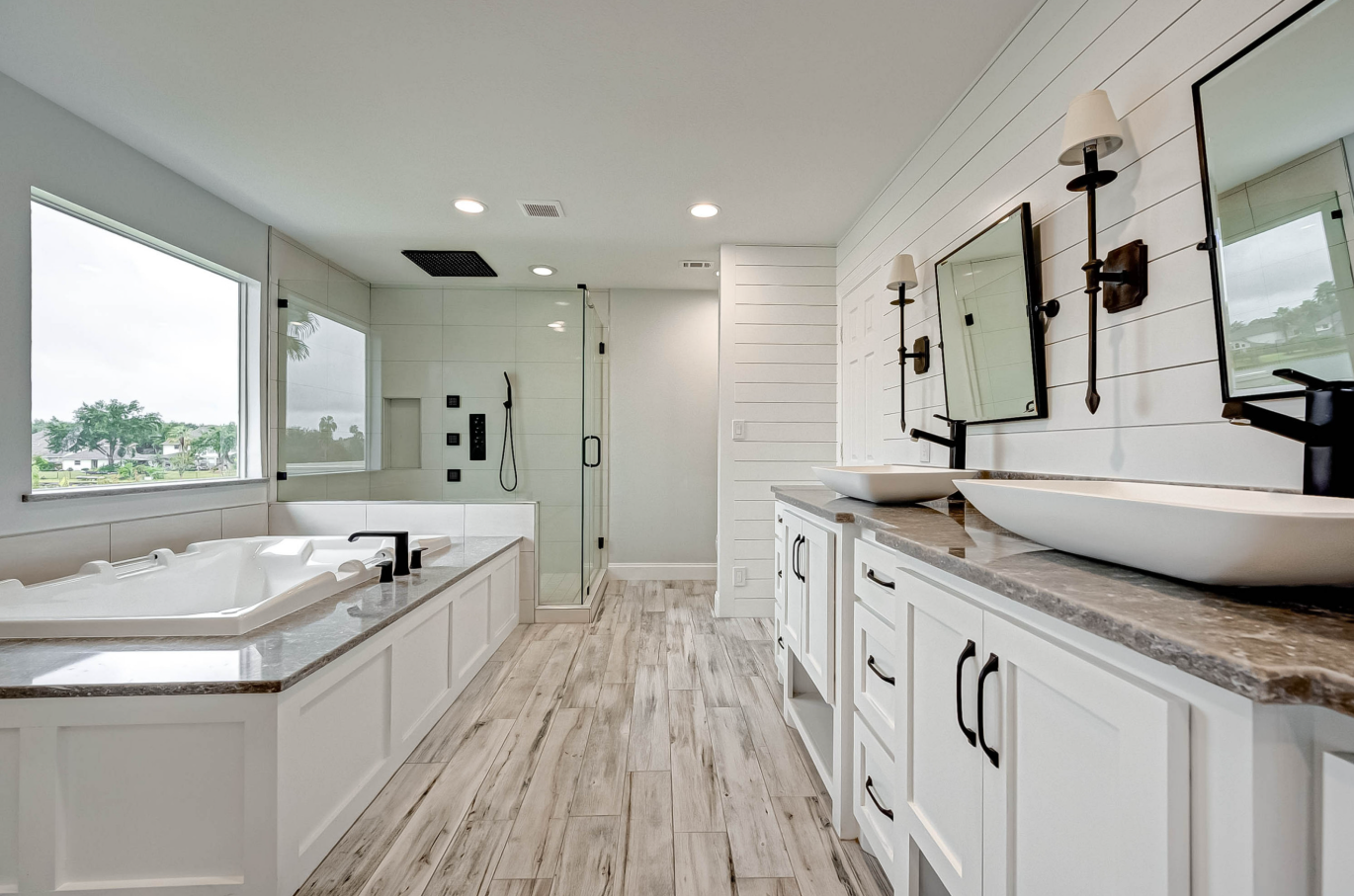 primary bathroom with soaking tub, dual vessel sinks, and glass shower