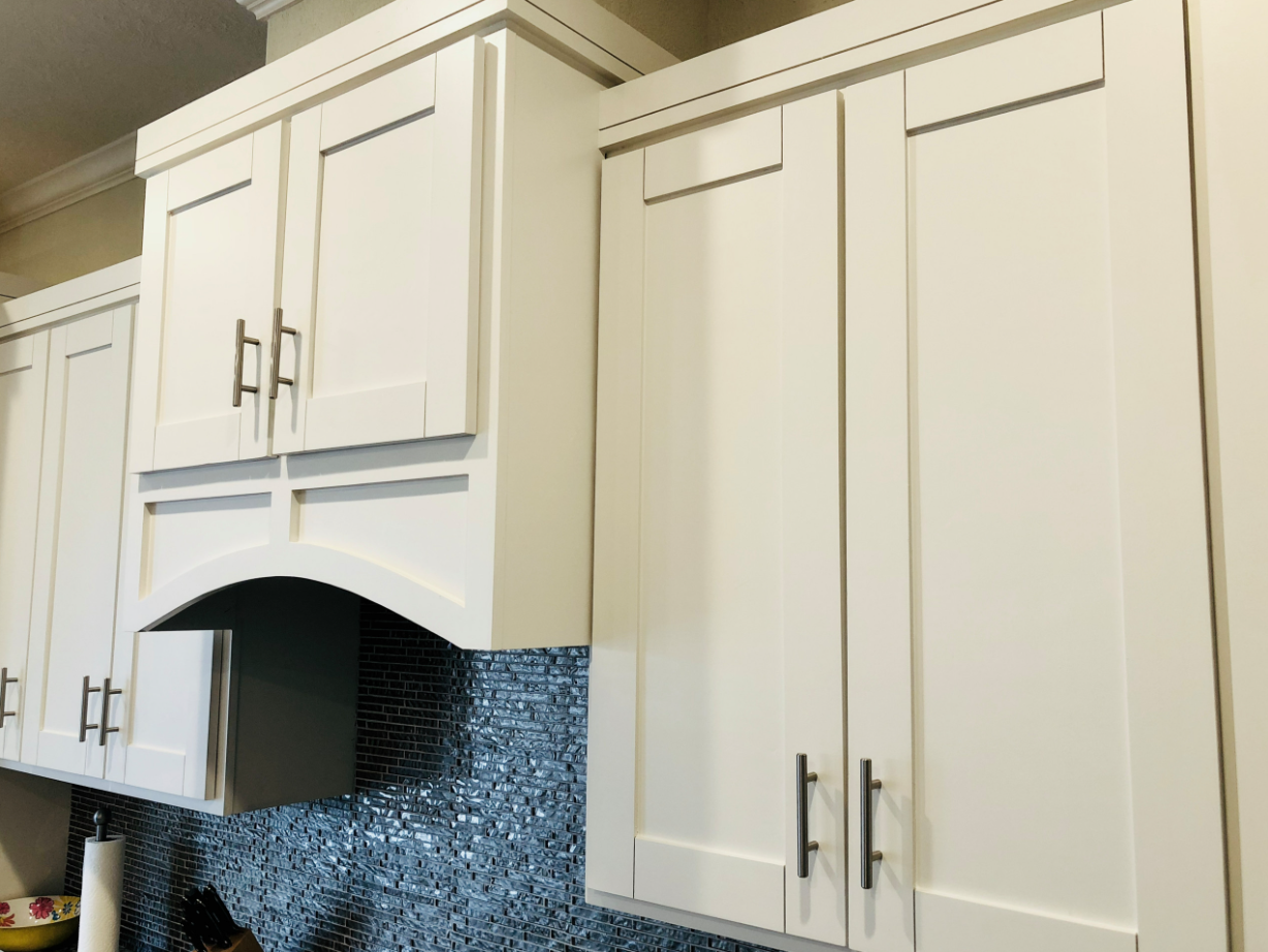 detail of varied cabinet heights and modern shaker cabinet design above mosaic backsplash