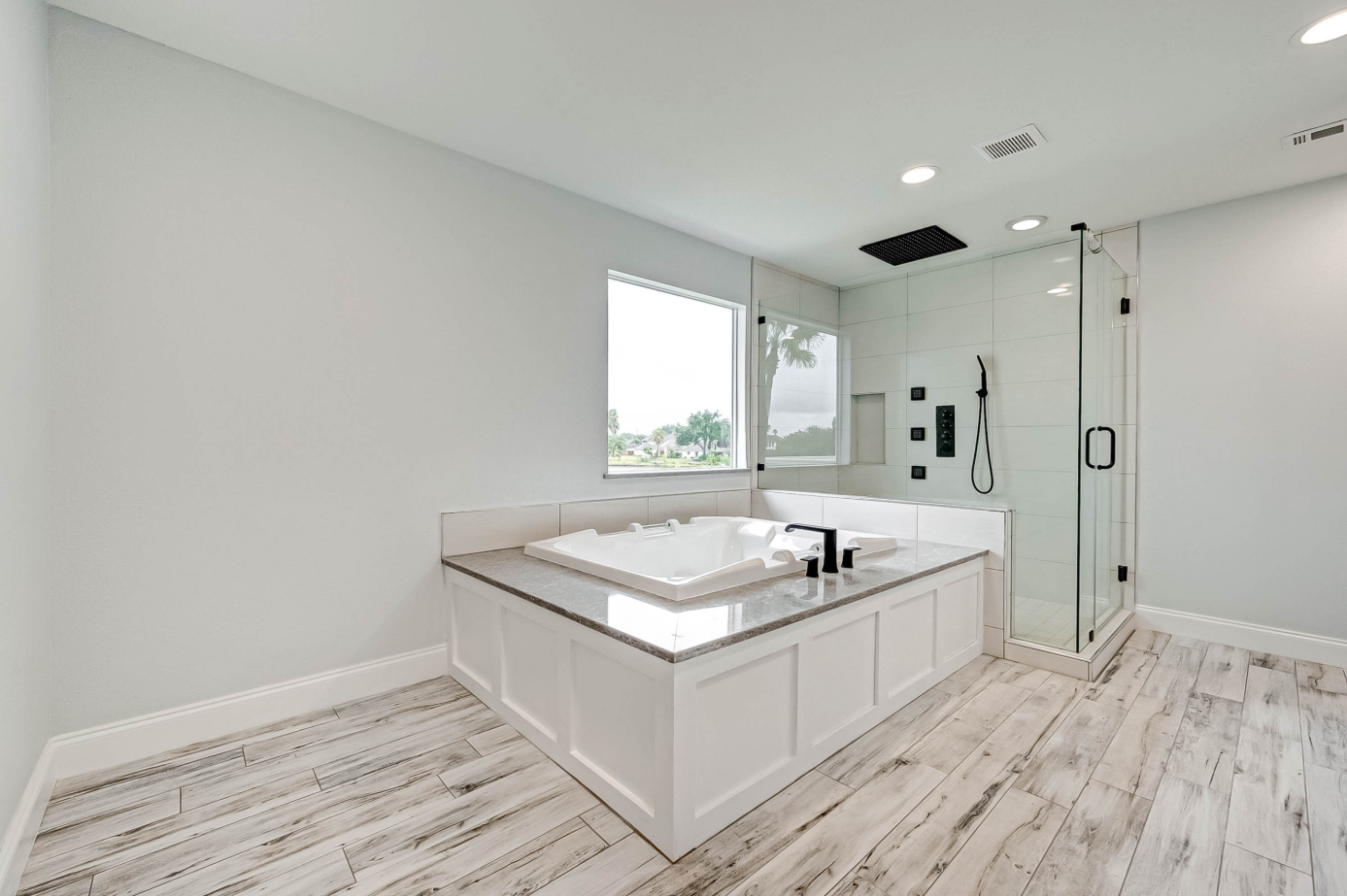 modern master bath with bathtub, glass shower with body jets, and wood-look tile flooring